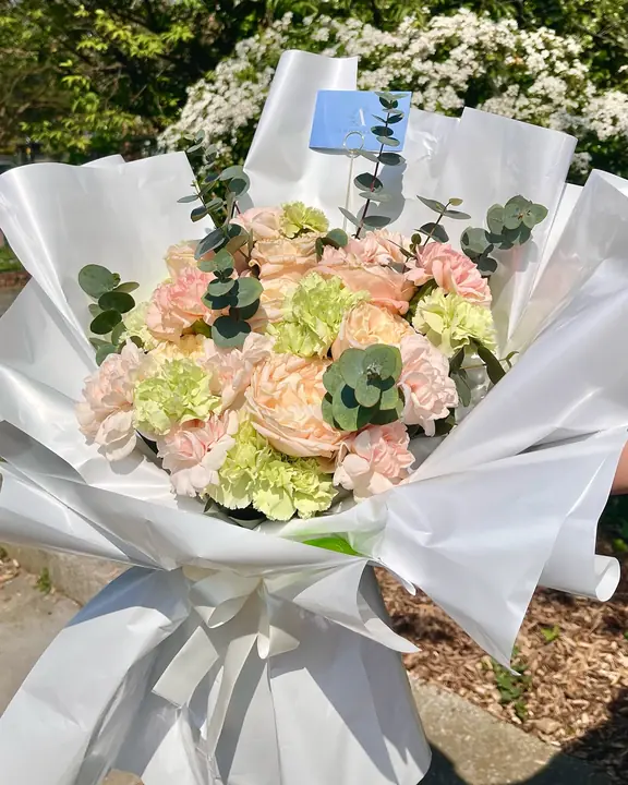 Peach rose and green carnation bouquet in white wrap